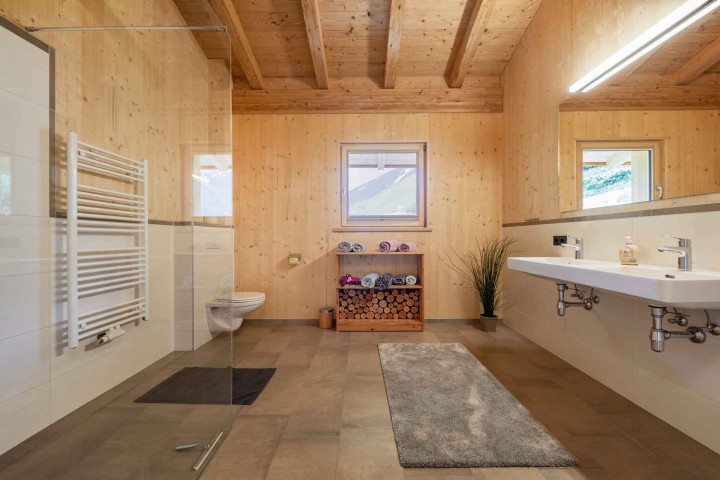 Modernes Bad mit Glasdusche, WC und zwei Waschbecken sowie Fenster