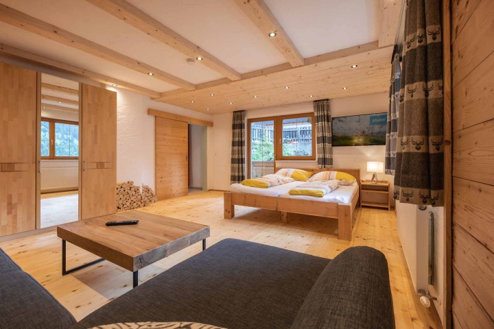 Ferienwohnung mit warmen Holzwänden und einem komfortablen Bett im Raum sowie einer Couch und Zugang zum Bad