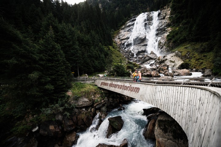 Family on a bridge in front of a waterfall