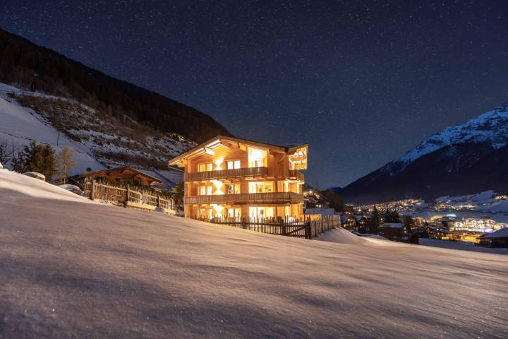 The Alpenkönigin house in the evening. A house in the mountains, surrounded by snow-covered ground and a picturesque winter landscape.
