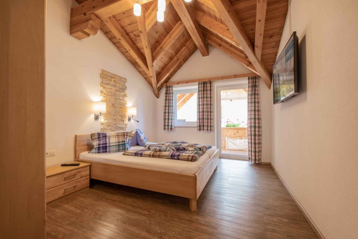 A bedroom with wooden ceiling beams and a cozy bed that creates an inviting atmosphere.