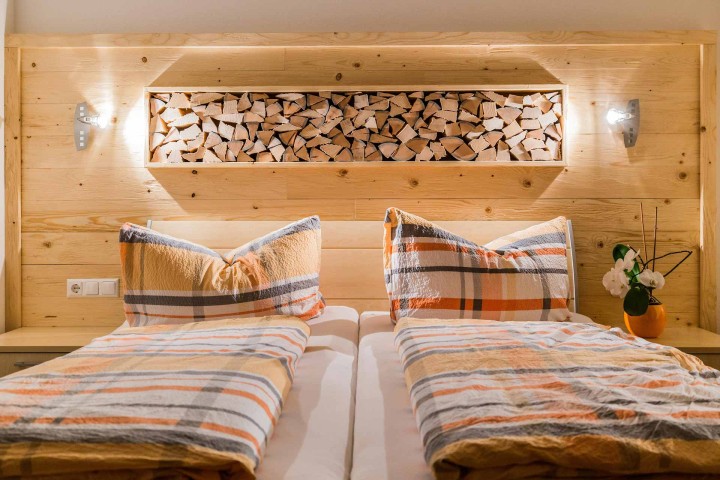 Ein Schlafzimmer mit zwei Betten, ausgestattet mit orange und weißen Bettdecken, vermittelt ein warmes und einladendes Ambiente. Holzdekorelemente.