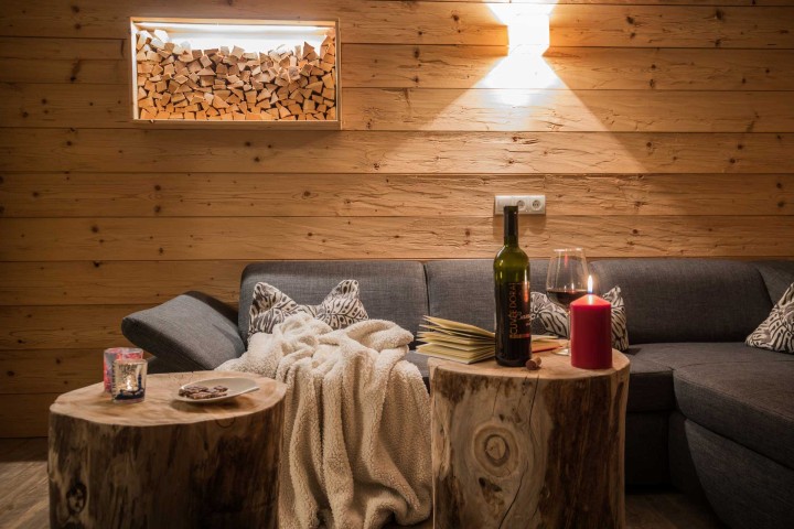 Cozy living room with a couch, a table and a bottle of wine, ideal for relaxing evenings.
