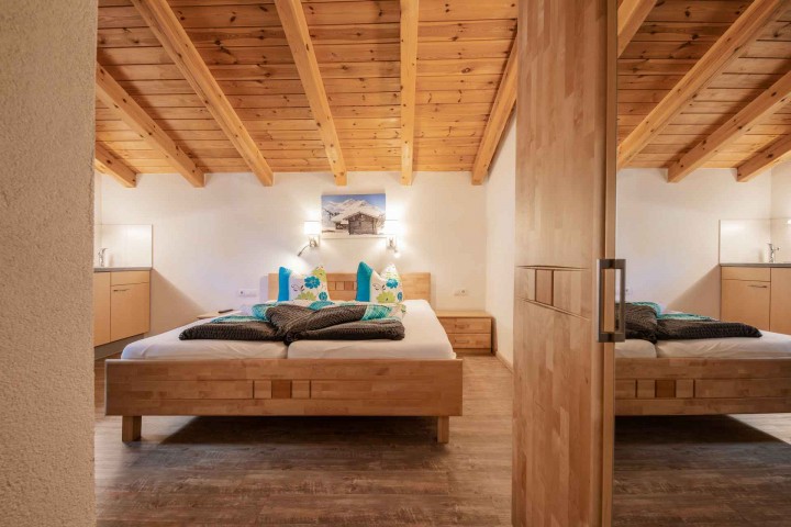 Cozy bedroom with wooden ceiling and an inviting bed, ideal for relaxing nights.