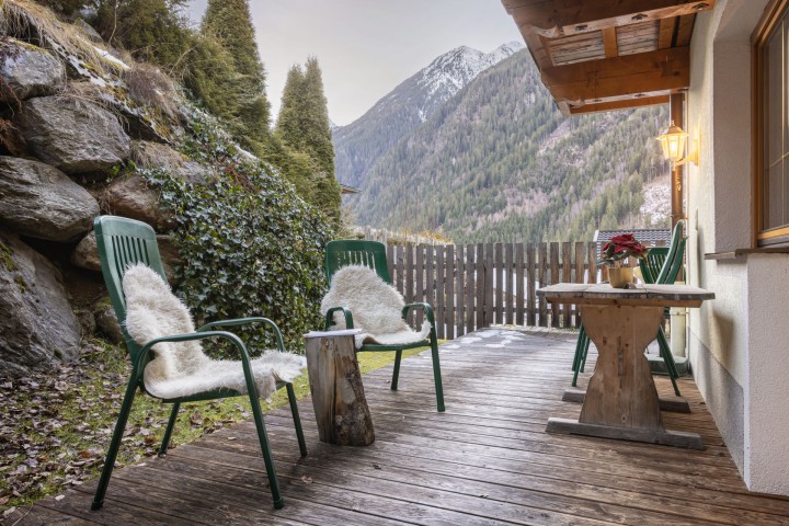  Eine Holzterrasse an einem Haus, die eine einladende Außenfläche für Entspannung und Geselligkeit bietet.