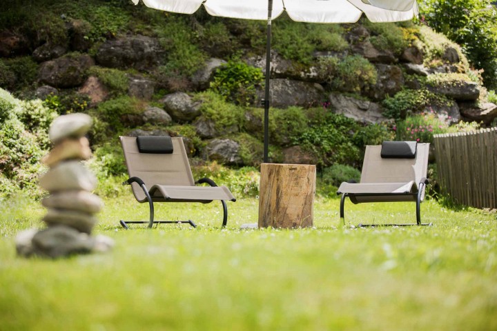Two sun loungers under a parasol on a green lawn, ideal for relaxing outdoors.