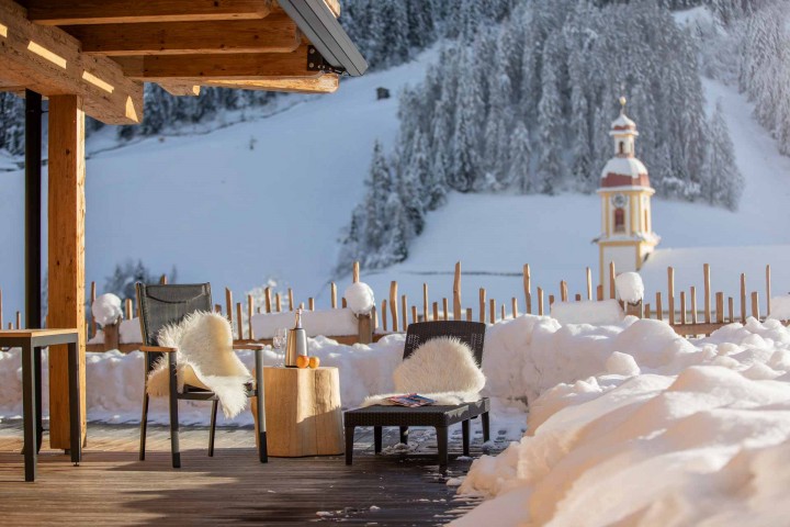 Gemütliches Holzdeck mit Stühlen, umgeben von einer beeindruckenden Berglandschaft im Hintergrund