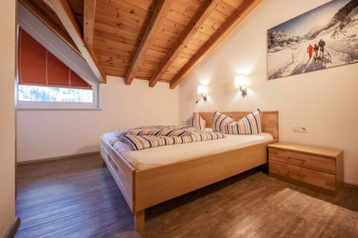 A bedroom with wooden ceiling beams and a cozy bed that creates an inviting atmosphere.