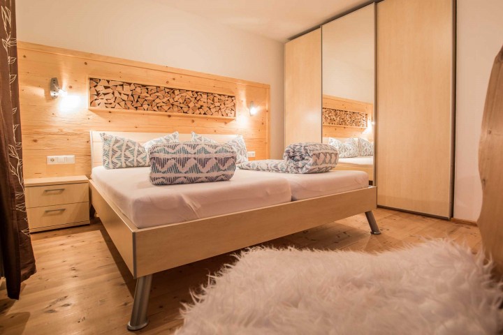 Bedroom view with a bed and a rustic wooden wall that conveys warmth and comfort.