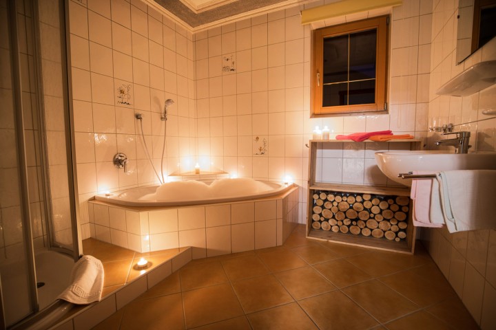 Mit kerzen geschmücktes Bad mit Dusche, Schaumbad in einer Badewanne und Waschbecken