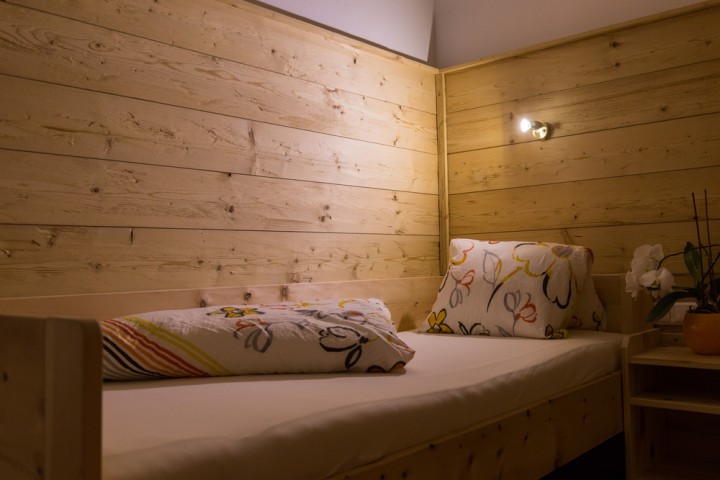 Gemütliches Einzelbett hinter vor einer Holzwand