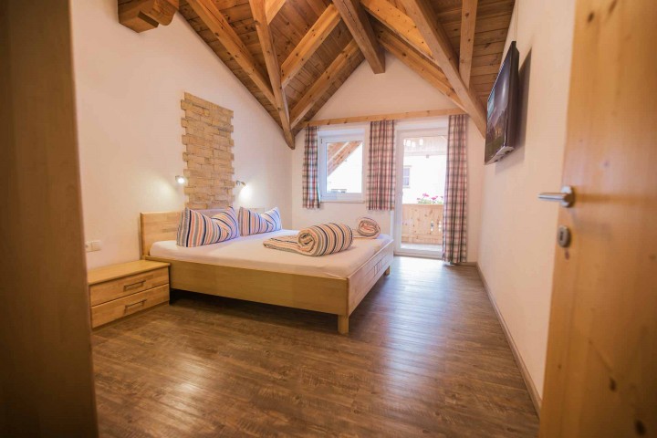 Ein Schlafzimmer mit Holzbalken und einem gemütlichen Bett, das eine einladende Atmosphäre schafft.