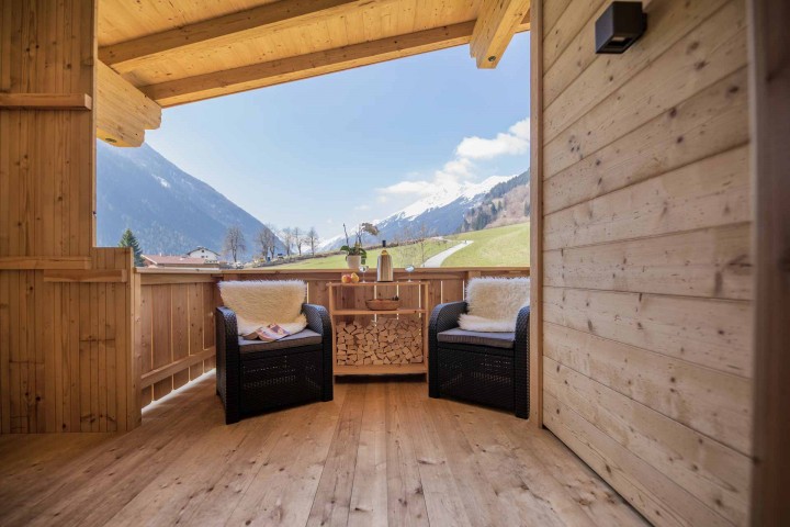 Ausblick vom Balkon auf das Stubaital mit Häusern und Bergen im Hintergrund bei strahlendem Sonnenschein