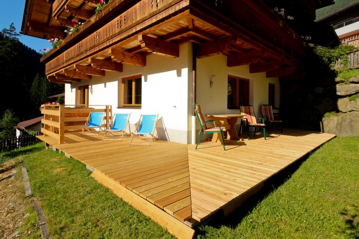  Eine Holzterrasse an einem Haus, die eine einladende Außenfläche für Entspannung und Geselligkeit bietet.