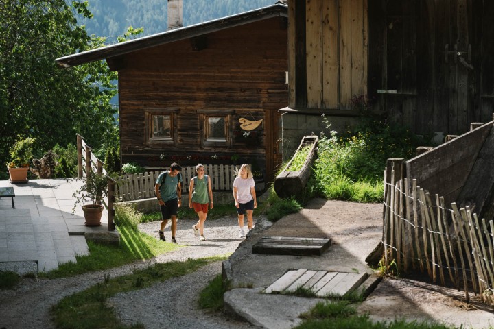 Idyllic mountain hut in the Stubai Valley, Tyrol. 3 hikers on one path