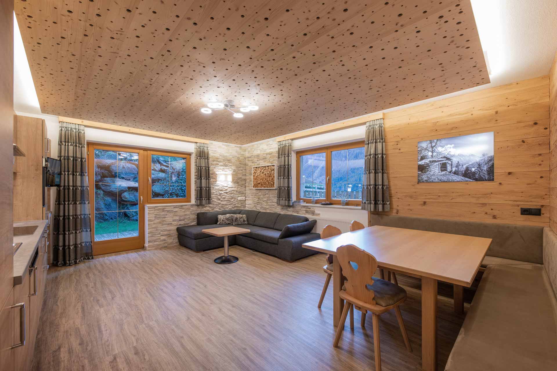 Adlerhorst vacation apartment: Cozy living room in the Adlerhorst vacation apartment with sofa, TV and red carpet. Accommodation in the Stubai Valley, Tyrol.