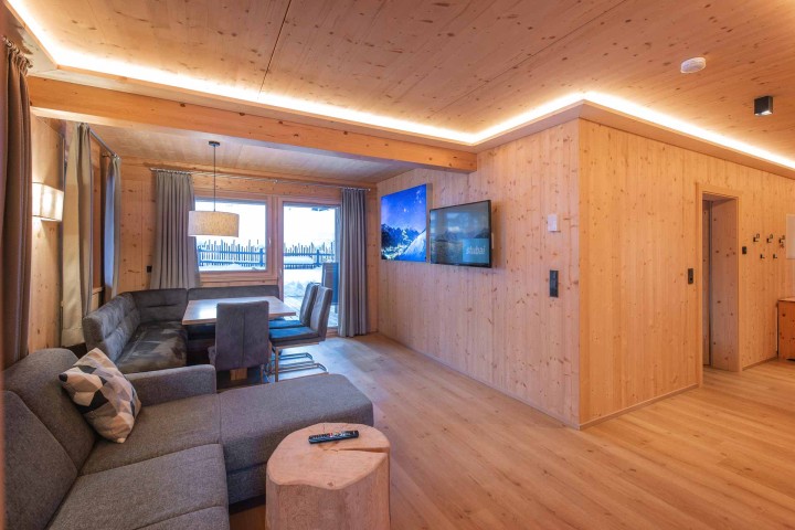 Wohn- und Essbereich mit Couch, Tisch und Stühlen sowie Zugang zum Balkon