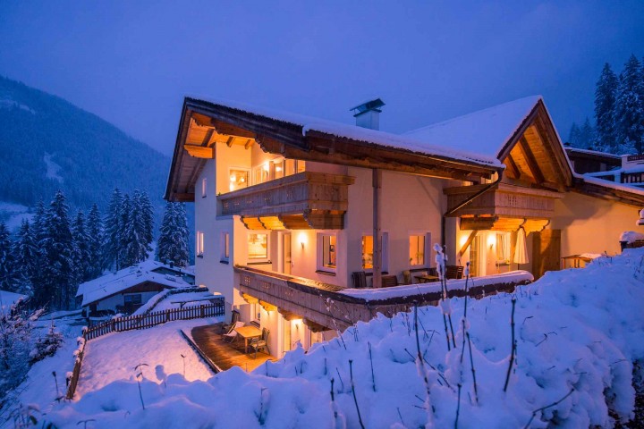 Unterkunft im Stubaital: Das Haus Alpenkönigin am Abend. Ein Haus in den Bergen, umgeben von schneebedecktem Boden und einer malerischen Winterlandschaft.
