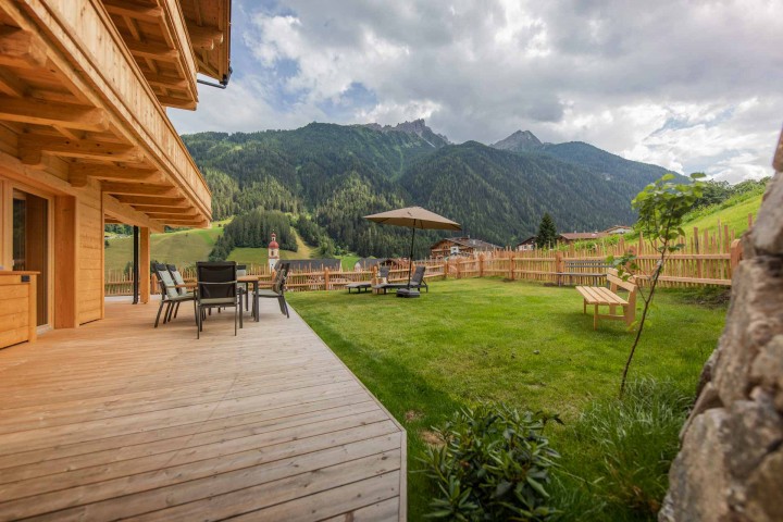 Große Terrasse mit Sitzmöglichkeiten auf der Terrasse und im grünen Gras. Herrlicher Ausblick auf die Berge und umgeben von der Natur
